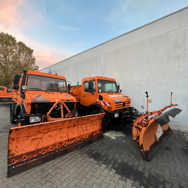 Zwei kleine Bagger-ähnliche Fahrzeuge im Hof geparkt.