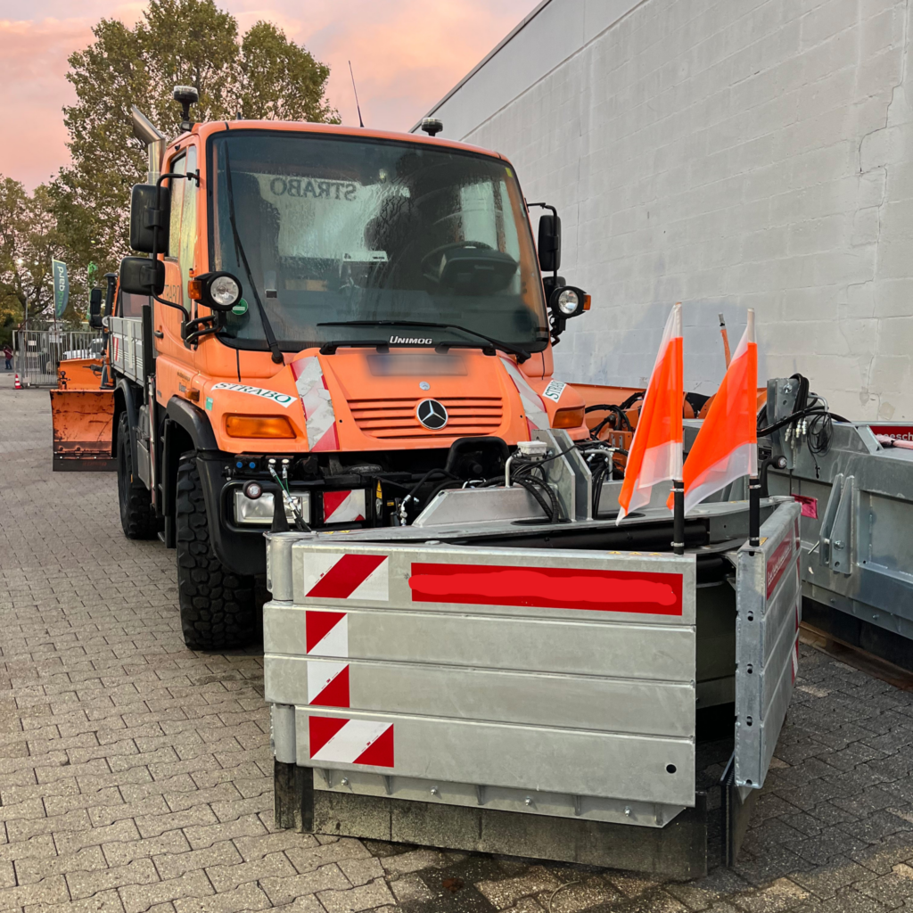 Kleiner Transporter mit Schneeschieber im Hof geparkt.